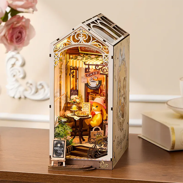 Miniature model of a cafe scene inside a decorative box on a wooden surface.