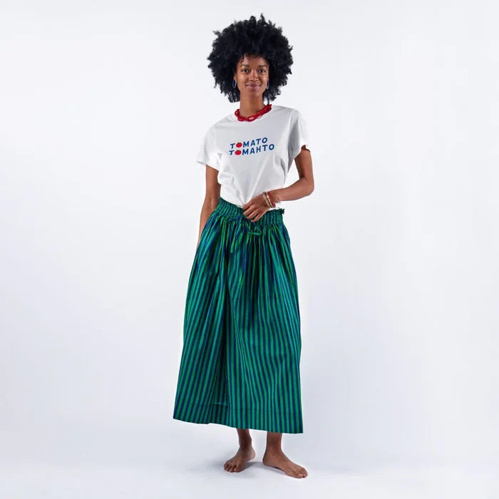 Woman wearing a white t-shirt with text and a green striped skirt on a white background
