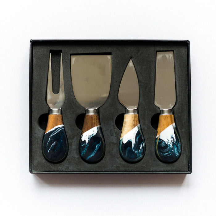 Set of four cheese knives with blue handles in a black box on a white background