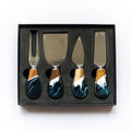 Set of four cheese knives with blue handles in a black box on a white background